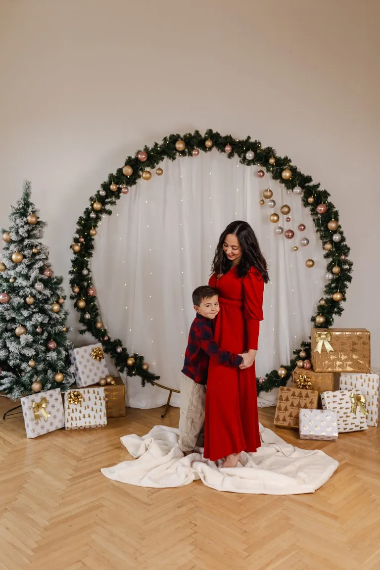 Celý kruhový oblouk z chvojí s ozdobami, vedle zasněžený stromek a dárky